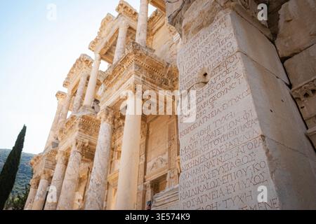 Antica iscrizione greca scolpita su parete di marmo presso la Biblioteca Celso di Efeso, in Turchia, con dettagliata architettura romana Foto Stock