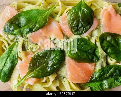 Vista dall'alto del piatto di pasta fresca con ampi tagliatelle a nastro (fettuccine o tagliatelle) condite con fette di salmone affumicato e fresco Foto Stock