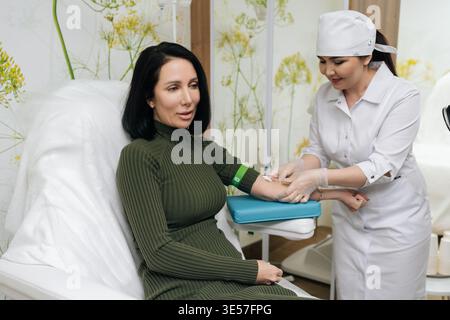 Flebotomo medico positivo prelievo di campione di sangue dal braccio paziente femminile che indossa il laccio emostatico, preparazione per l'analisi di laboratorio e la salute Foto Stock