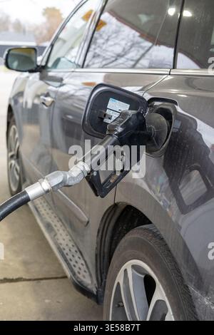 Primo piano dell'ugello del carburante inserito nel serbatoio dell'auto presso la stazione di rifornimento. Concetto di trasporto e consumo energetico. Foto Stock