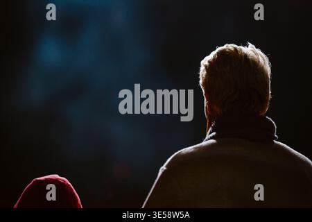 Sagome di una donna e di un bambino che guardano uno spettacolo in un cinema o in un teatro buio. Foto Stock