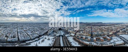 Ampia vista panoramica dalla stazione ferroviaria di Nyugati, tetti innevati, Parlamento a sinistra, ponti sul Danubio, colline di Buda, cielo blu Foto Stock