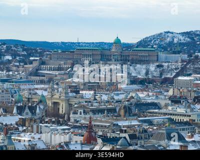 Palazzo reale del Castello di Buda, collina innevata, primo piano dei tetti di Pest, area di Keleti, cielo invernale coperto Foto Stock