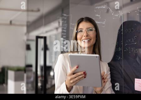 Donna piuttosto professionale che usa un tablet sul posto di lavoro Foto Stock