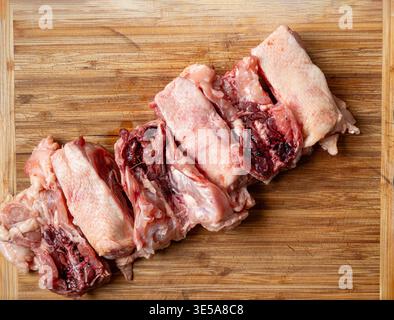 Una fila di dorsi di pollo crudi freschi tagliati a pezzi su un tagliere di legno. Primo piano, niente gente Foto Stock