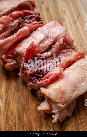 Una fila di dorsi di pollo crudi freschi tagliati a pezzi su un tagliere di legno. Primo piano, niente gente Foto Stock