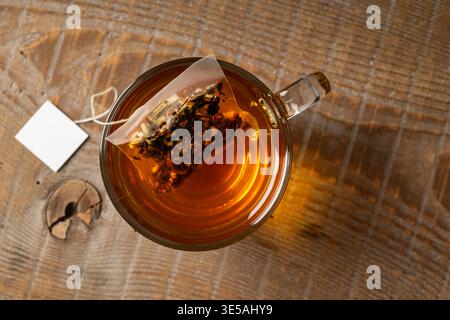 Tazza di tè in vetro su un tavolo di legno con bustina di tè all'interno. Vista dall'alto. Foto Stock