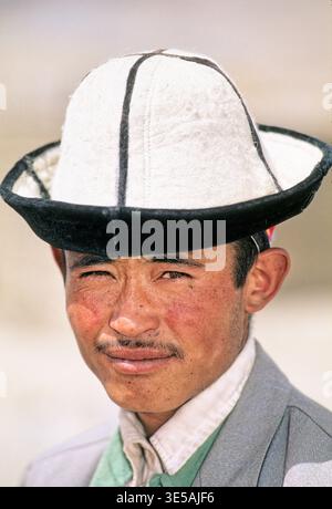 Un giovane si trova in Uzbekistan con un cappello tradizionale. La sua espressione mostra fiducia e orgoglio. Lo sfondo è sfocato. Foto Stock