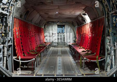 Vano passeggeri vuoto di un elicottero militare d'epoca con file di sedili in tela rossa Foto Stock