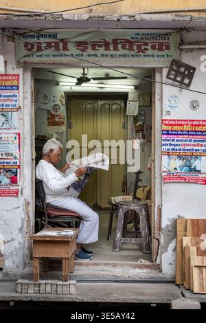 Uomo anziano che legge un giornale in una porta, Jodhpur, India Foto Stock