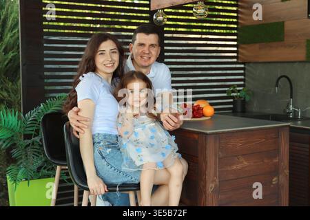 Festeggiamenti in un ambiente informale. I genitori sorridono con una figlia vicino al banco cucina Foto Stock