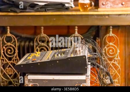Mixer audio con molti cavi collegati, posizionato sulla custodia dell'apparecchiatura in un ambiente pub Foto Stock