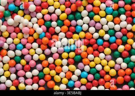 La collezione densa di perle di zucchero colorate in primo piano, che mostrano una consistenza lucida e varie dimensioni decorazioni di dolciumi rotonde Foto Stock