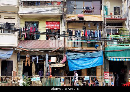 Gli edifici della città di ho chi Minh mostrano la vita di tutti i giorni con abiti appesi all'esterno. La gente fa le sue abitudini nella strada trafficata qui sotto. Foto Stock