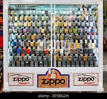 Un negozio a ho chi Minh City espone in vendita una grande collezione di accendini Zippo. Molti design sono visibili dietro il vetro. Foto Stock