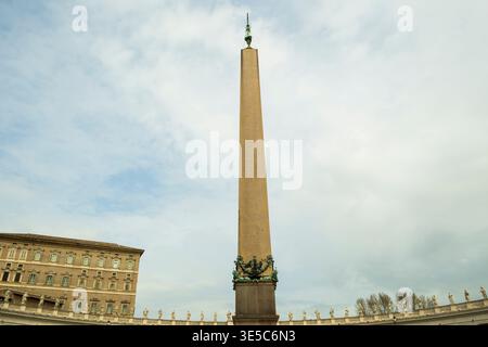 L'obelisco Vaticano si erge alto contro un cielo nuvoloso, fiancheggiato da edifici storici. Foto Stock
