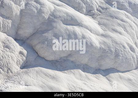 Vista ravvicinata delle suggestive terrazze in travertino bianco a Pamukkale, Turchia, che mostrano i depositi minerali naturali che creano questo mesm unico Foto Stock