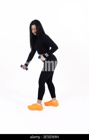 Donna che fa affondamenti con manubri in studio Foto Stock