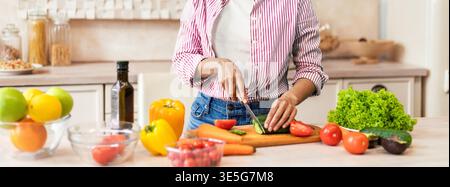 La donna prepara verdure fresche nella cucina moderna sorridendo durante il giorno Foto Stock