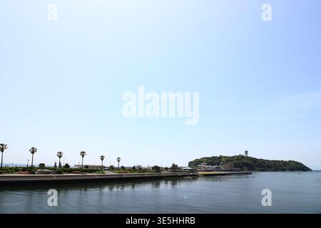 Una vista lontana dell'isola di Enoshima all'inizio dell'estate, vista dal lato costiero di Kugenuma del ponte Enoshima Benten Foto Stock