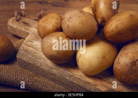 Patate crude, sparse su un tagliere, primo piano, nessuna gente Foto Stock