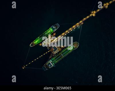 Vista aerea delle petroliere attraccate in un terminal offshore durante le operazioni notturne. Le navi illuminate stanno trasferendo il carico in mare aperto. Foto Stock