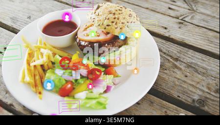 Hamburger su piatto in ceramica con patatine fritte, insalata e salsa, icone colorate su un tavolo in legno Foto Stock