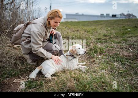 Donna che accarezza il suo cane labrador bianco in un campo all'aperto Foto Stock