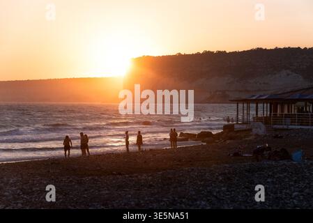 Kourion, Cipro - 22 agosto 2021: Persone sulla spiaggia di Kourion che godono di un'ora d'oro in riva al mare con un vibrante tramonto Foto Stock