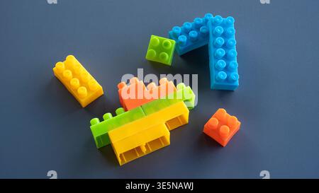 Blocchi di costruzione in plastica colorati impilati in Creative Formation su sfondo scuro Foto Stock