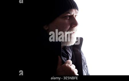 Ritratto di un uomo anziano che indossa un cappello e una giacca di lana. Carismatico anziano dai capelli grigi uomo, cappello, giacca, sguardo laterale con un sorriso.Vista profilo Foto Stock