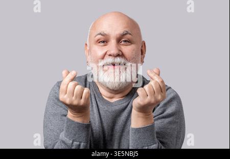Simbolo cuore mani amore segno cuore posa mano. La mano del vecchio nel fare un gesto cardiaco con un dito, simboleggiando l'amore. Uomo anziano allegro uomo anziano toothy Foto Stock