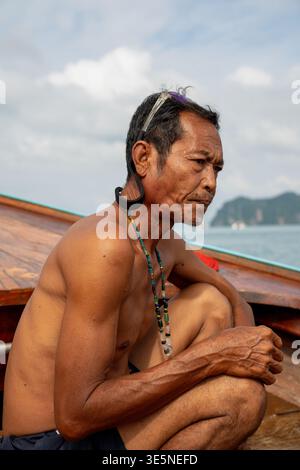 Pescatore seduto su una barca a coda lunga in thailandia Foto Stock