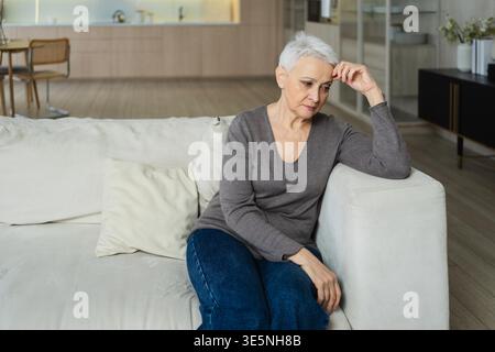 Triste stanco malato solo deluso anziana donna seduta a casa da solo. Nonna matura infelice che sperimenta dolore relativa morte cattiva notizia. Stressato anziana che soffre di solitudine Foto Stock