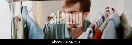 Uomo adulto che sceglie i vestiti per la rivendita online o la pianificazione del guardaroba Foto Stock