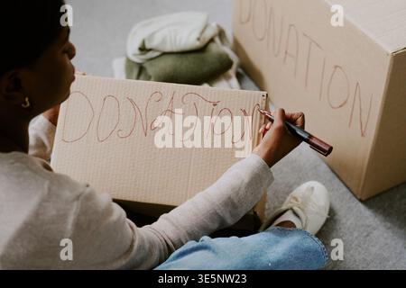 Black Woman etichettando le scatole per donazioni per la campagna benefica Foto Stock