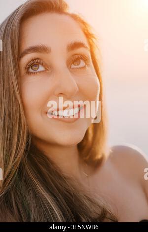 Donna sorride al tramonto ritratto di una giovane donna felice che guarda il cielo durante l'ora d'oro con un'espressione gioiosa e fiduciosa Foto Stock