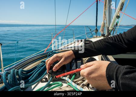 Corde di regolazione delle mani del marinaio sul ponte dello yacht a vela Foto Stock