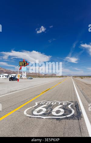 Amboy, California / Stati Uniti - 13 aprile 2023: Il famoso cartello stradale della Route 66 dipinto su asfalto con Roys Cafe, motel e stazione di servizio lungo l'autostrada Foto Stock