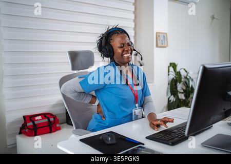 Lavoratrice sanitaria che soffre di mal di schiena mentre lavora in ufficio Foto Stock
