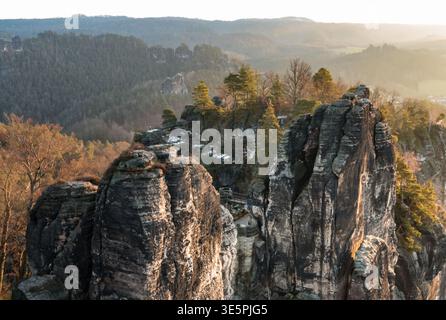 Splendida vista dal Basteiaussicht delle formazioni rocciose di Bastei con il ponte tra loro e le rovine del Castello di Neurathen Rock, riscaldate da morbide... Foto Stock