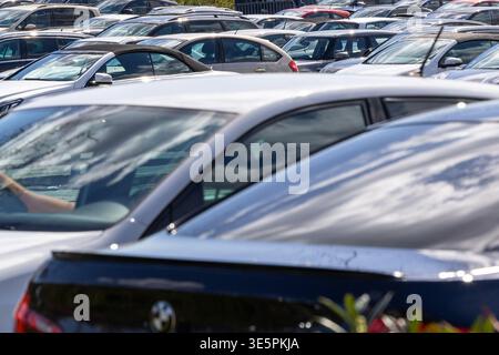 File di auto parcheggiate in un ampio parcheggio, che riflette la mobilità urbana e la densità di traffico quotidiana in Germania Foto Stock