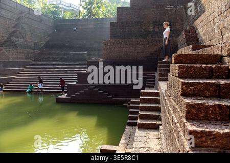 Turista donna che si erge sugli antichi gradini di pietra del tempio di Sree Peralassery nel Kerala, in India Foto Stock