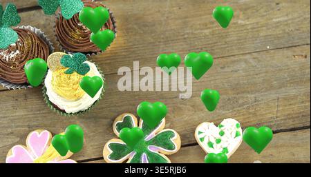 Esposizione di cupcake con topper shamrock e cuori verdi fluttuanti su un piano rustico, spazio per copiare Foto Stock