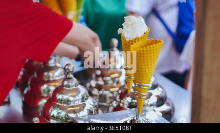 Distributore che serve gelatine rinfrescanti in coni di waffle presso un bancone all'aperto Foto Stock