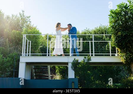 Coppia afroamericana sul balcone donna che raggiunge uomo appoggiato bacia mano in abito formale in amore Foto Stock