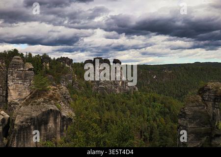 Spektakulärer Ausblick von der Bastei auf die markanten Felswände und tiefen Wälder des Elbsandsteingebirges unter einem Wolkenhimmel Foto Stock