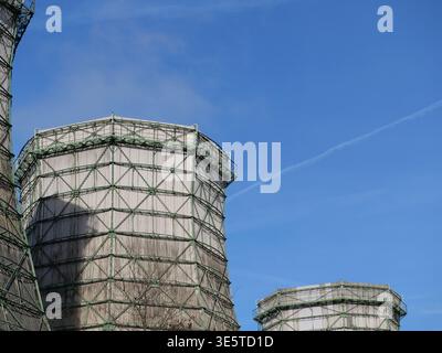 Torri di raffreddamento industriali con ponteggi in metallo verde e rivestimento in legno contro un cielo blu. Vista ad angolo basso dell'architetto della stazione di raffreddamento dell'impianto elettrico Foto Stock