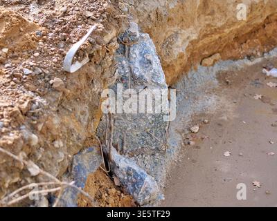 fondazioni in calcestruzzo esposte in trincee di detriti, primo piano di un pilastro in calcestruzzo rotto con arrugginite sotto terra, dettagli del sito di scavo che mostrano la posa del terreno Foto Stock