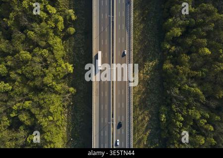 Traffico auto in movimento su autostrada, vista aerea. Campagna strada attraverso la foresta. Viaggio, consegna e concetto logistico Foto Stock
